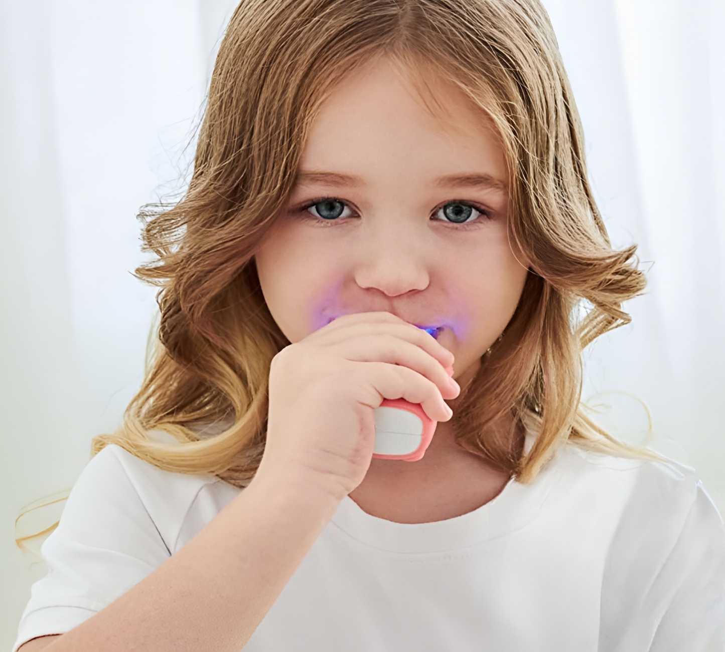 Young blonde girl using an electric U-brush against a white background